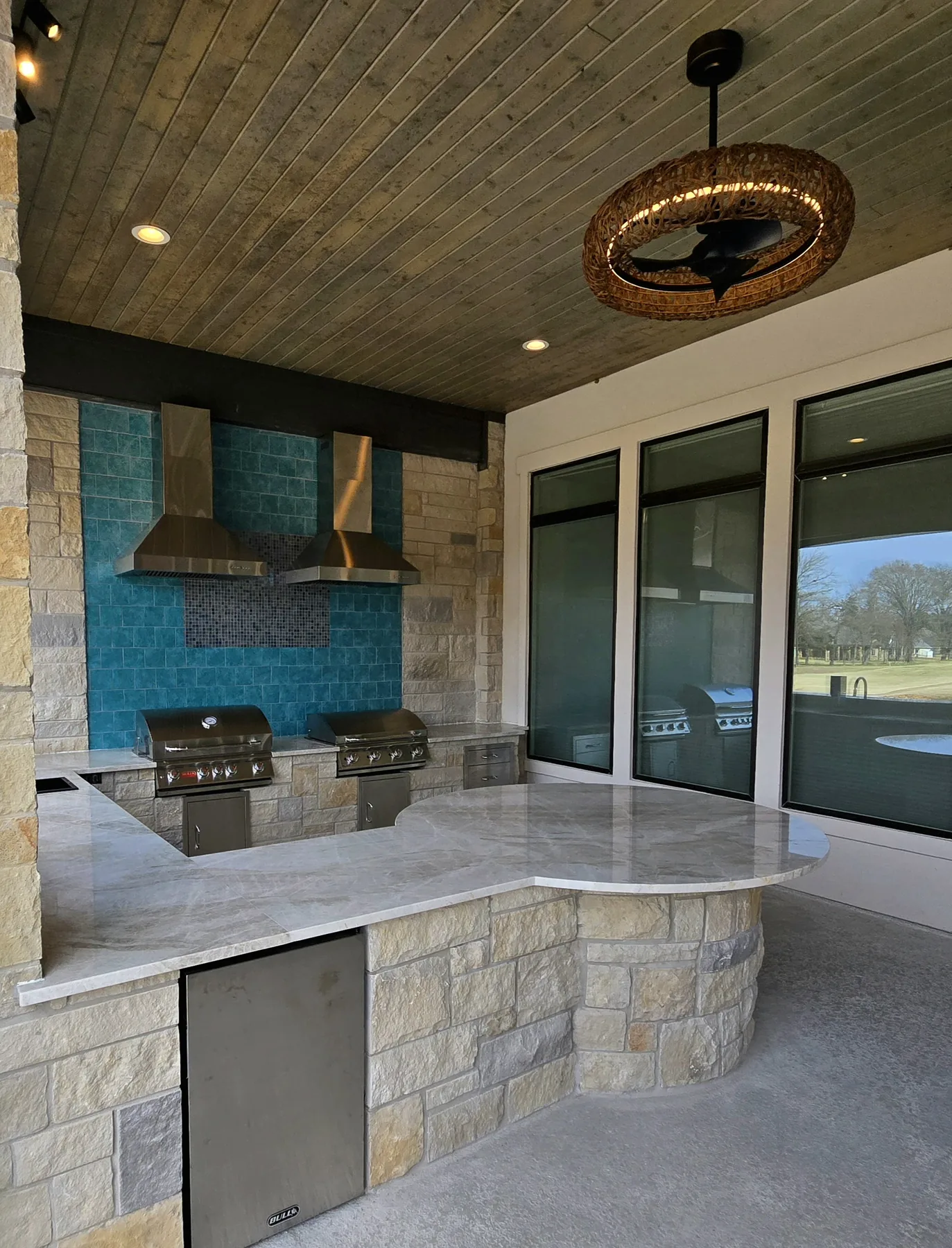 Covered outdoor kitchen with two grills, turquoise tile and stone counters